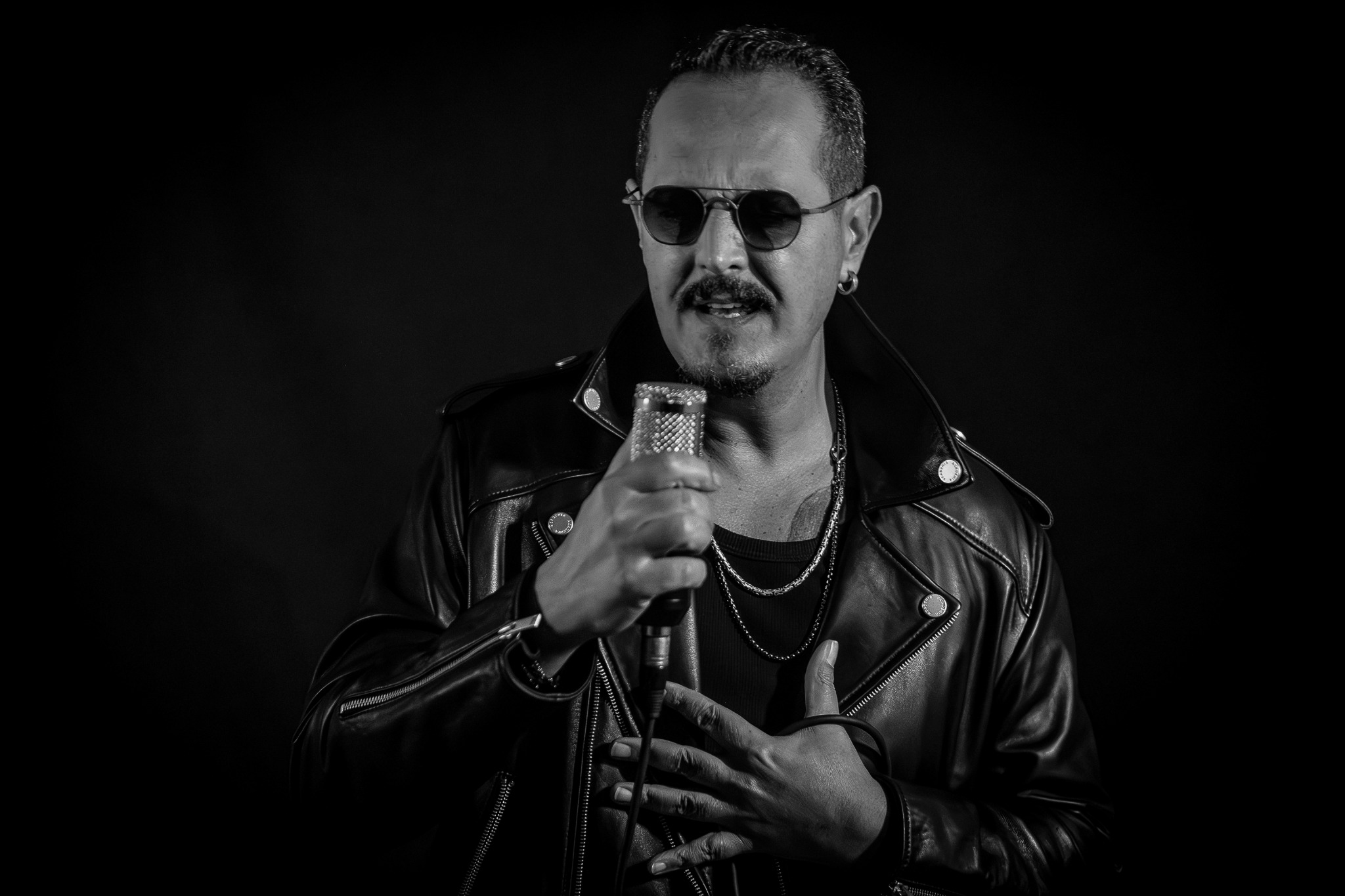 Tolga Tüyel mikrofonla siyah beyaz sahne portresinde
